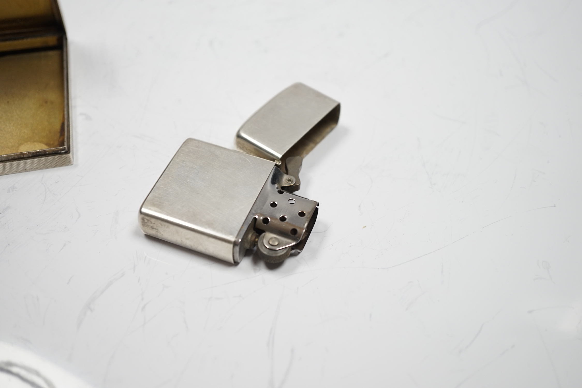 A sterling cased Zippo lighter, 71mm, together with a 1930's engine turned silver cigarette case.